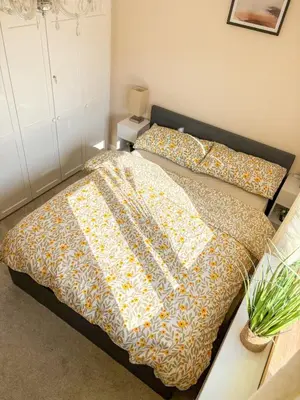 a bedroom with a bed with a comforter on it at Home in Upminster in Upminster