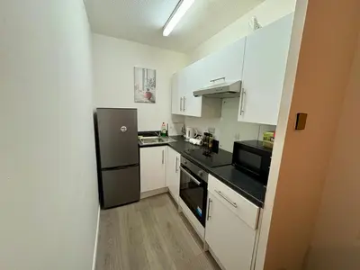 a small kitchen with white cabinets and black appliances at Central One-Bedroom Flat - Free Private Parking in Chesterton