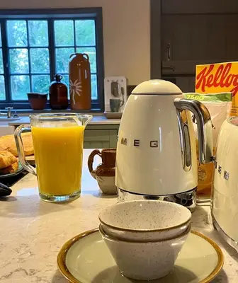 a kitchen counter with a tea kettle and a glass of orange juice at Park Farm in Thornham Magna
