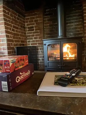 a book and a remote control on a counter with a fireplace at Park Farm in Thornham Magna
