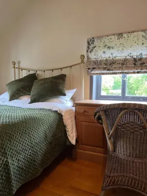 a bedroom with a bed and a window and a chair at Park Farm in Thornham Magna