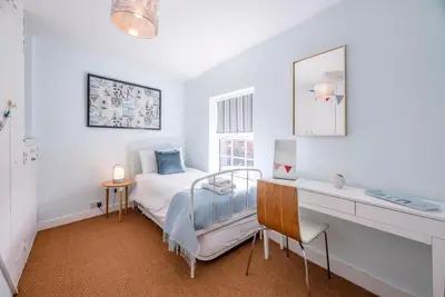 a bedroom with a bed and a desk and a window at Stones Throw, Aldeburgh in Aldeburgh