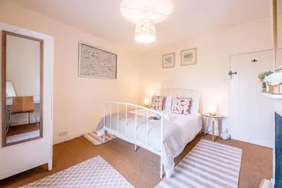 a bedroom with a white bed with pink pillows at Stones Throw, Aldeburgh in Aldeburgh