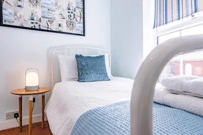 a bedroom with a bed and a table with a lamp at Stones Throw, Aldeburgh in Aldeburgh