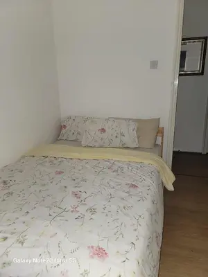 a bed with a floral bedspread and pillows on it at The Home 2 in Mile End