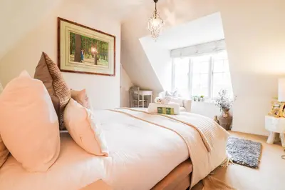 a bedroom with a large white bed with pillows at Beautifully Designed Cottage Free WiFi in Rivenhall
