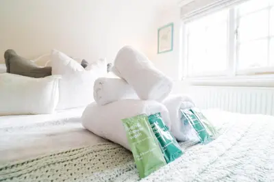 a pile of towels sitting on top of a bed at Beautifully Designed Cottage Free WiFi in Rivenhall