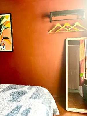 a bedroom with a mirror and a orange wall at Hurrell Cottage in Cambridge