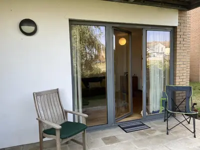 two chairs sitting on a patio with sliding glass doors at Alices’s Beachside Haven in Harwich