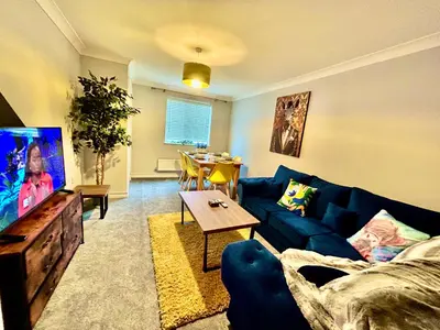 a living room with a blue couch and a table at 4 Bedroom House - DISC0UNTS - Parking, Contractors, Group, Family in Colchester