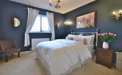 a blue bedroom with a bed and a chair at Family home in Great Dunmow for up to 5 guests in Great Dunmow