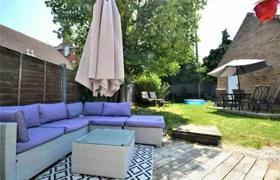a purple couch and an umbrella on a patio at Family home in Great Dunmow for up to 5 guests in Great Dunmow