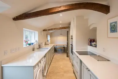 a kitchen with white counters and a long counter top at The Old Cottage - Sudbourne, near Orford in Sudbourne