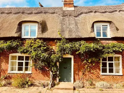 a red brick house with a thatched roof at The Old Cottage - Sudbourne, near Orford in Sudbourne