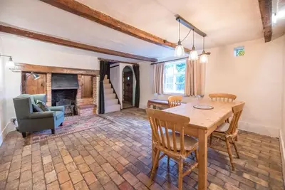 a living room with a table and a fireplace at The Old Cottage - Sudbourne, near Orford in Sudbourne