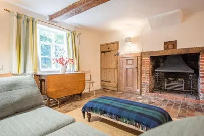 a bedroom with a fireplace and a desk and a bed at The Old Cottage - Sudbourne, near Orford in Sudbourne