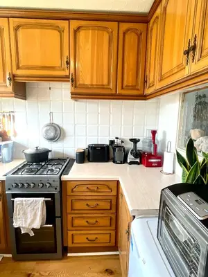 a kitchen with wooden cabinets and a stove top oven at Lea Valley Nature Reserve Bright Home with Private Garden - 40 min to London by Train in Nazeing
