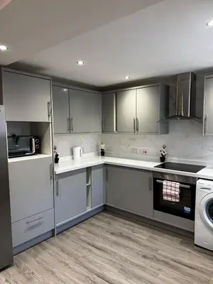a kitchen with white cabinets and a washer and dryer at Paramount Luxe Loft- 3 bedrooms, 4 beds cosy home in Laindon