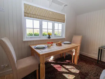 a dining room with a wooden table and a window at The Woodshed in Clacton-on-Sea