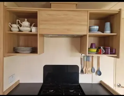 a kitchen with a stove and cabinets with utensils at House of Eminence Holidays in Saint Osyth