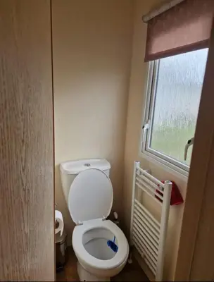 a small bathroom with a toilet and a window at House of Eminence Holidays in Saint Osyth