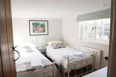 a bedroom with two beds and a window at Beautifully refurbished 3 bedroom cottage in Ashdon