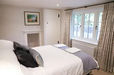 a bedroom with a white bed and a window at Beautifully refurbished 3 bedroom cottage in Ashdon