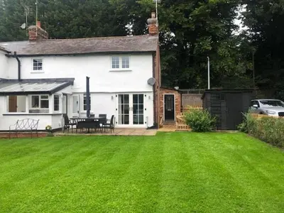 a white house with a lawn in front of it at Beautifully refurbished 3 bedroom cottage in Ashdon