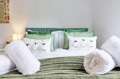 a bedroom with a white bed with green and white pillows at Luxury 4-Bed Family Home in Epping with Parking by LMV Property in Epping