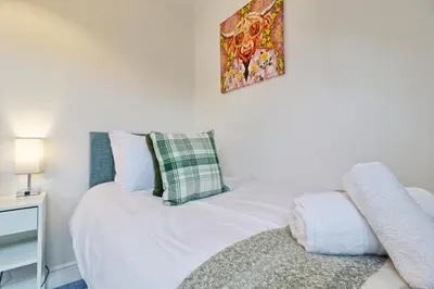 a bedroom with a white bed and a picture on the wall at Luxury 4-Bed Family Home in Epping with Parking by LMV Property in Epping