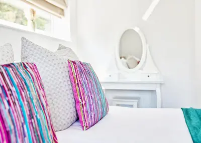 a white couch with colorful pillows and a mirror at Luxury 4-Bed Family Home in Epping with Parking by LMV Property in Epping