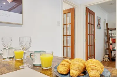 a table with a plate of croissants and glasses of orange juice at Luxury 4-Bed Family Home in Epping with Parking by LMV Property in Epping