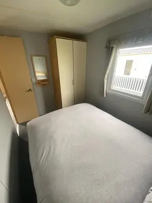 a bedroom with a white bed and a window at Highfield Grange Holiday Park Clacton in Little Clacton
