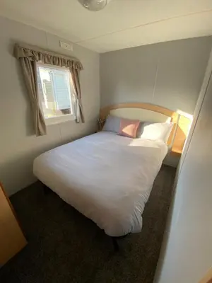a bedroom with a large white bed with a window at Highfield Grange Holiday Park Clacton in Little Clacton