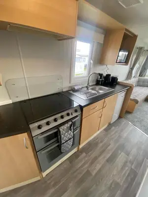 a small kitchen with a stove and a sink at Highfield Grange Holiday Park Clacton in Little Clacton