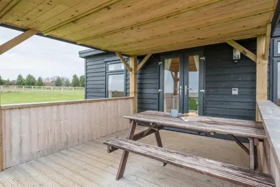 a picnic table on the deck of a black house at River Lodge, Aldeburgh in Aldeburgh