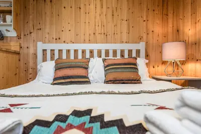 a bedroom with a white bed with wooden walls at River Lodge, Aldeburgh in Aldeburgh