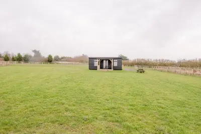 a tiny house in a field with a fence at River Lodge, Aldeburgh in Aldeburgh