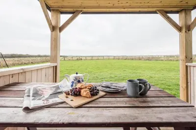 a picnic table with a plate of fruit and a magazine at River Lodge, Aldeburgh in Aldeburgh