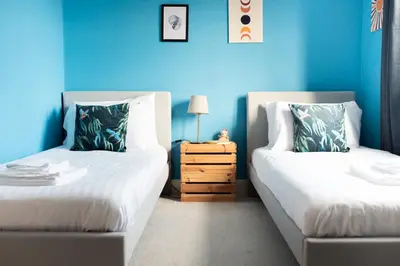 a blue room with two beds and a night stand at Spacious 3-Bed Townhouse Florence Villa Near River & City in Chesterton