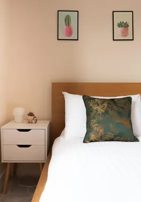 a bedroom with a bed and a nightstand with a cactus at Spacious 3-Bed Townhouse Florence Villa Near River & City in Chesterton