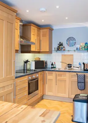 a kitchen with wooden cabinets and a stove top oven at Spacious 3-Bed Townhouse Florence Villa Near River & City in Chesterton