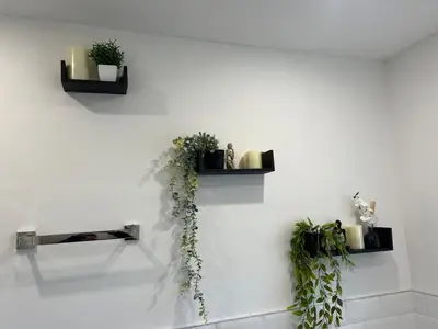 a white wall with two shelves with plants on it at Salvation View 2 Bed Apartment in Hadleigh