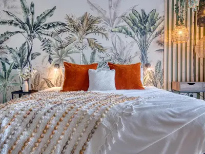 a bedroom with a white bed with a tropical wallpaper at Cambridge - hot tub, sauna, parking, pool table in Trumpington