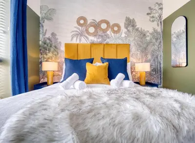 a bedroom with a large bed with blue and yellow pillows at Cambridge - hot tub, sauna, parking, pool table in Trumpington