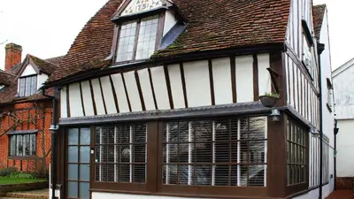 an old building with large windows and a roof at Chinnerys Country Cottage in Cavendish
