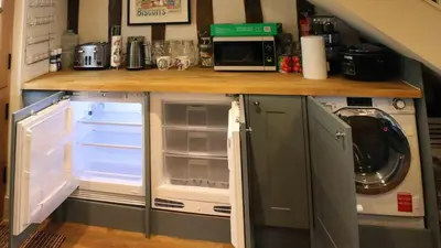 a kitchen with an open refrigerator and a microwave at Chinnerys Country Cottage in Cavendish