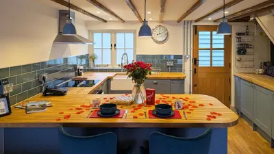 a kitchen with a wooden table with flowers on it at Chinnerys Country Cottage in Cavendish
