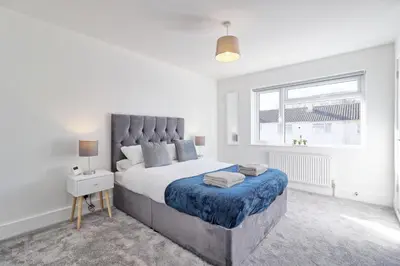 a white bedroom with a large bed and a window at 3 Bed, Sleeps 6, Wifi, Free Parking in Writtle