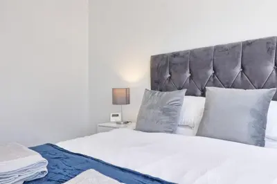 a bedroom with a white bed with a gray headboard at 3 Bed, Sleeps 6, Wifi, Free Parking in Writtle